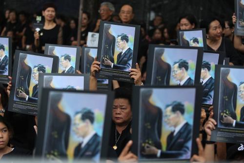 The people, who attend the first rehearsal of the royal procession, raise the portrait of HM the late King Bhumibol Adulyadej over their heads with tear in their eyes, as the royal chariot is passing yesterday.